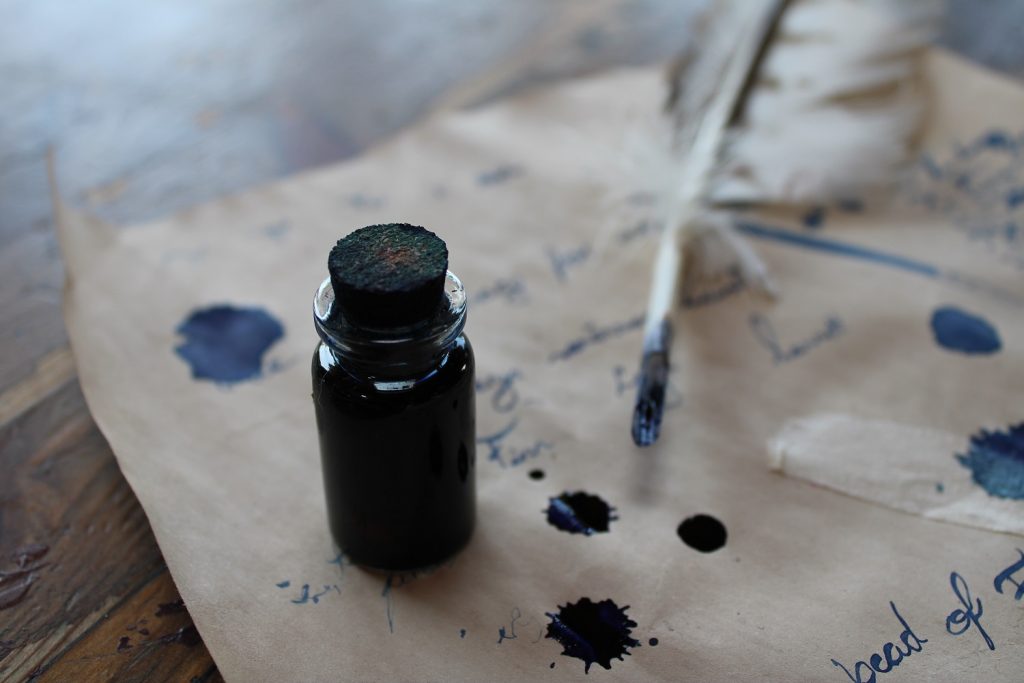 small ink bottle goose feather ink writing on parchment paper
