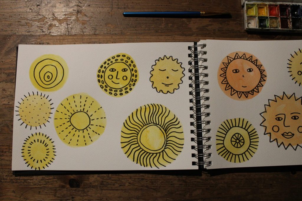 painted yellow suns in a a sketchbook brush and small water colour set