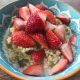 bowl with rhubarb millet porridge and freshly cut strawberries on top