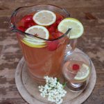 jug with elderflower drink, lemon slices and strawberries