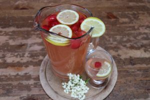 jug with elderflower drink, lemon slices and strawberries