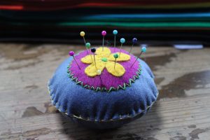 blue and purple felt pin cushion with a yellow flower