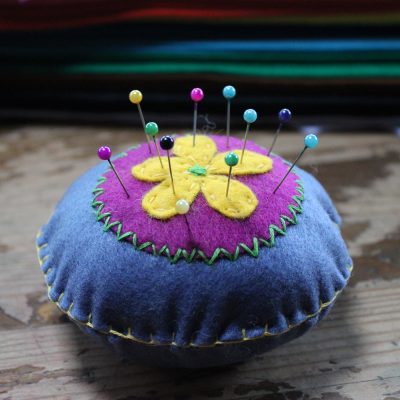 blue and purple felt pin cushion with a yellow flower