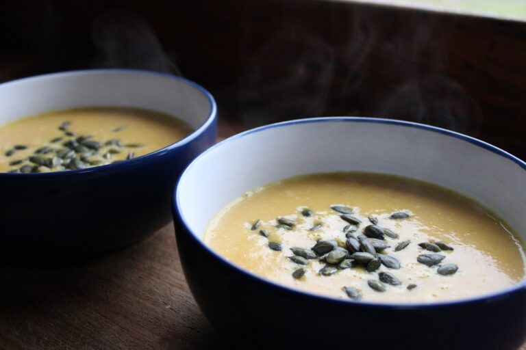 two bowls of carrot soup with pumpkin seeds